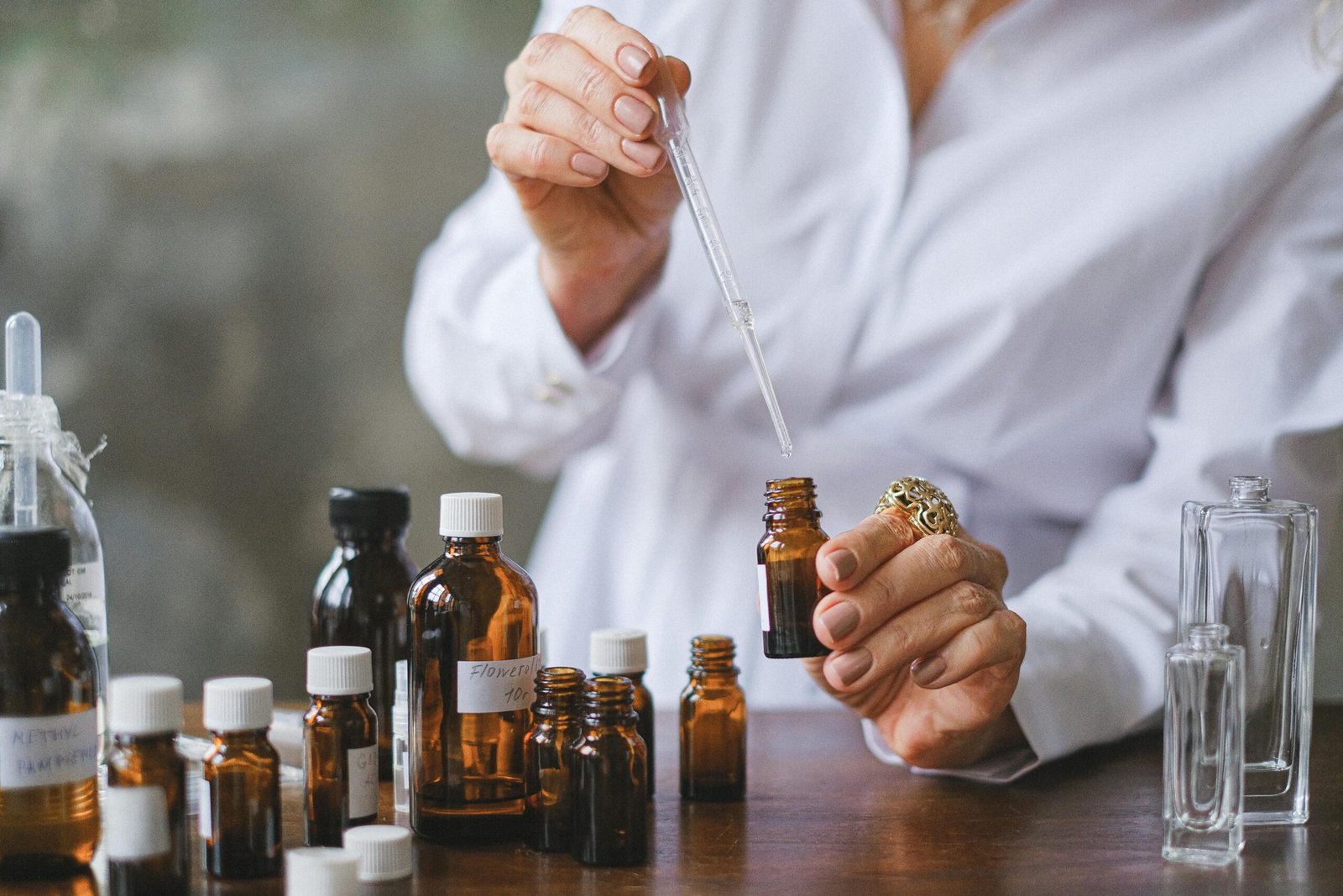 Close-up of hands handling amber glass bottles during an aromatherapy session.